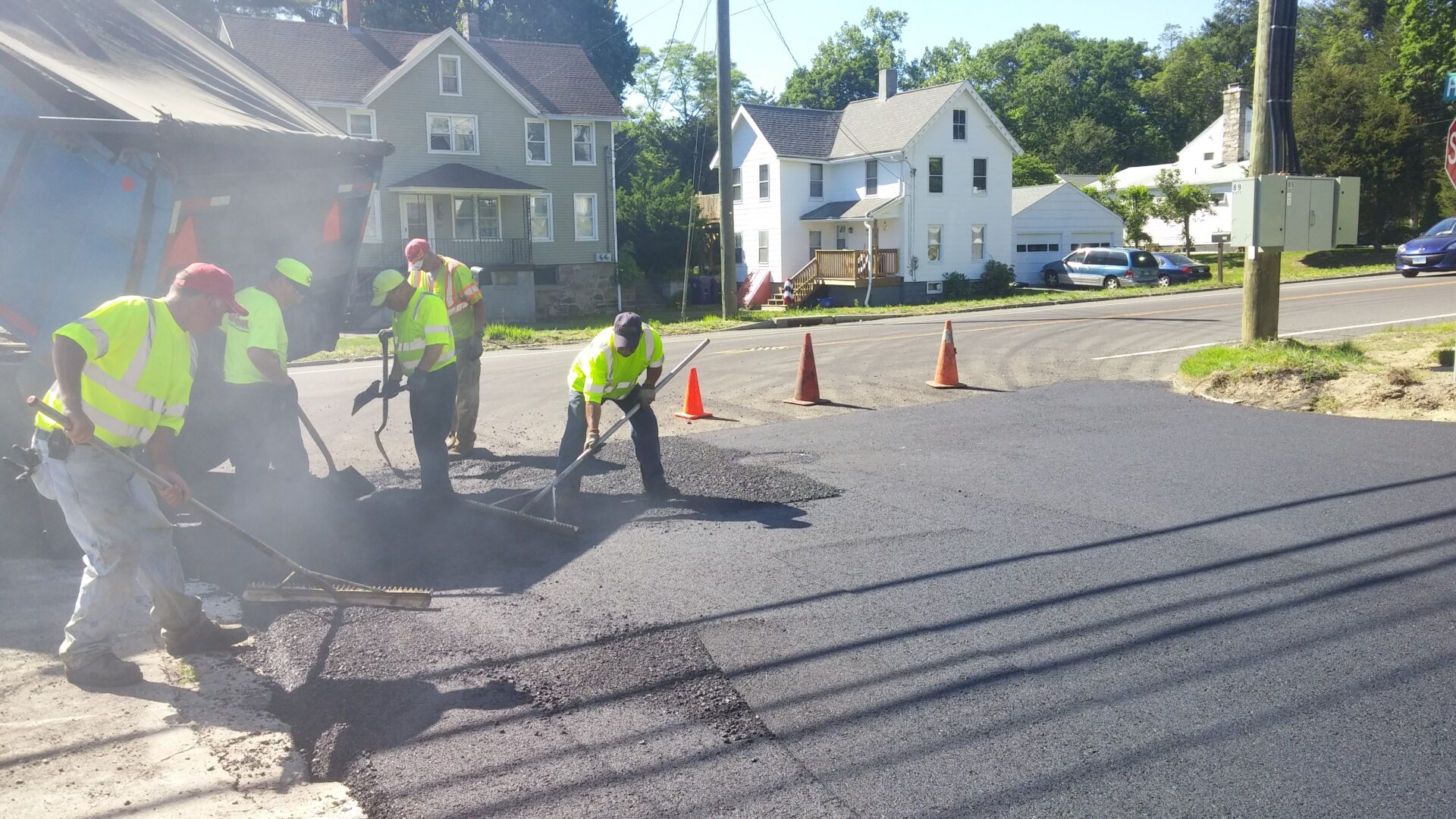 Two men working on a road with cones around them.