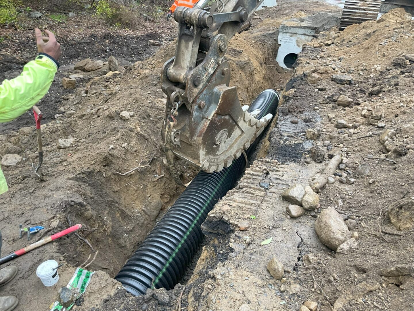 A pipe laying in the ground next to a pile of dirt.